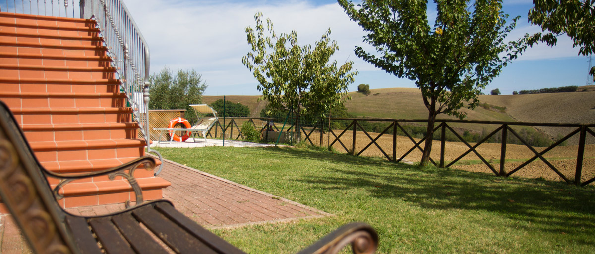 Blick von einer Gartenbank des Ferienhofs auf die Hügellandschaft der Marken